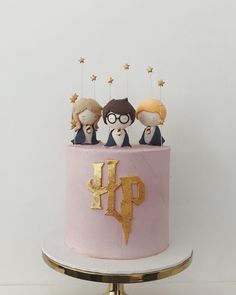 a pink and gold cake with harry potter figurines on top