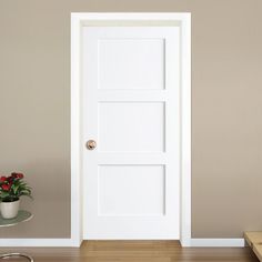 an empty room with a white door and wooden flooring next to a coffee table