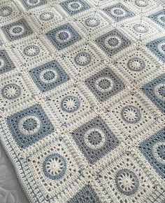 a blue and white crocheted blanket on top of a bed