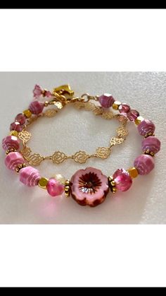 Lovely double strand beaded Premium Czech glass flower bracelet featuring Picasso pink turbine beads, Czech pink sea glass, pink cherub fire polished crystals, and single 15 mm pink Picasso pansy flower. All accented with antique gold plated daisies and shiny cubes. Satin Hamilton rose chain adds the perfect delicate second strand. Premium gold electroplated brass chain in satin finish with intricate rose flower pattern. Bracelet is beaded on professional Soft Flex beading wire with high quality Adjustable Pink Single Strand Beaded Bracelets, Adjustable Pink Single Strand Beaded Bracelet, Adjustable Single Strand Pink Beaded Bracelet, Pink Beaded Czech Glass Jewelry, Pink Faceted Bracelet Jewelry, Pink Glass Jewelry With Faceted Beads, Pink Faceted Jewelry Bracelet, Handmade Pink Glass Jewelry, Handmade Pink Czech Glass Jewelry