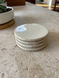 a stack of white plates sitting on top of a table next to a potted plant