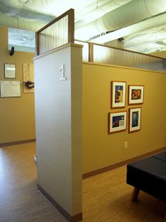 an empty room with pictures on the wall and a black bench in front of it