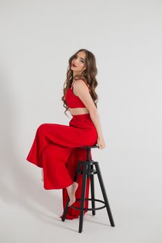 a woman in a red dress sitting on a stool