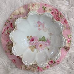 a pink and white plate with flowers on it sitting on a furnishing area