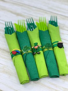 four green napkins with shamrock decorations are sitting on a wooden table next to each other