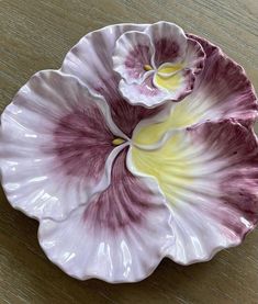 two purple and white flowers on a wooden table with one flower in it's center