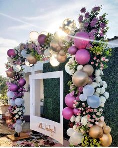 a decorated entrance with balloons and flowers on the outside, in front of a mirror