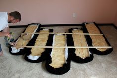 a man is working on some kind of bed made out of wood and sheepskins