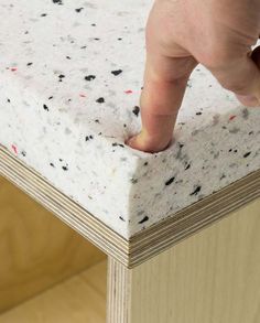 a hand is pointing at something on top of a table with white and black speckles