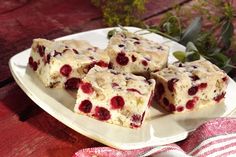 four pieces of cake on a white plate with flowers in the backgroung