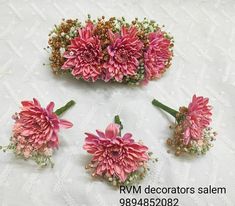 four pink flowers are arranged on a white tablecloth with lace and beading around them