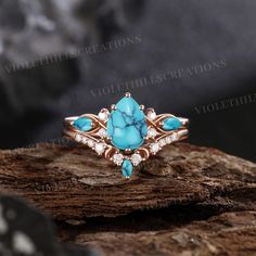 a turquoise stone and diamond ring sitting on top of a piece of wood with rocks in the background