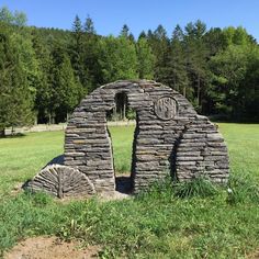 an old stone structure in the middle of a grassy field with trees in the background