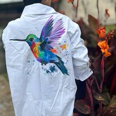 a man wearing a white jacket with a colorful hummingbird painted on it's back