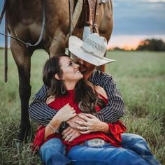 a man and woman sitting in the grass next to a horse