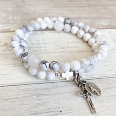 "This beautiful gemstone rosary bracelet features Snow Quartz beads as the paters and white Howlite beads as the aves. Each of our stretch and wrap rosary bracelets is a full rosary.  Small Glory rosary bracelets do not include the first three aves. Each bracelet also includes a \"bookmark\" crucifix medal.  This medal is moveable and can help you keep track of where you are at in your rosary as you pray throughout your day. (Cross and medal style may vary) Each bracelet is strung on durable ela Adjustable Hand-strung White Rosary Bracelet, White Gemstone Beads Stretch Bracelet For Meditation, White Hand Wrapped Stretch Bracelet With Round Beads, White Hand Wrapped Round Beads Stretch Bracelet, White Spiritual Rosary Bracelet, Adjustable White Rosary With 108 Beads, White Spiritual Rosary Bracelet With 8mm Beads, Adjustable White Spiritual Wrap Bracelet, White Spiritual Stretch Bracelet With Gemstone Beads