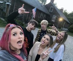 a group of people standing in front of a house with one pointing at the camera