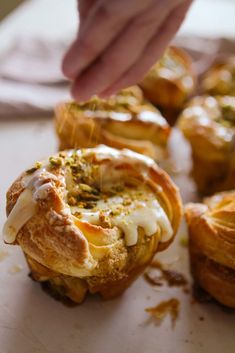 the pastry is being dunked with icing and sprinkled with pistachio