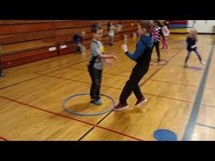 children are playing with a hoop on the gym floor