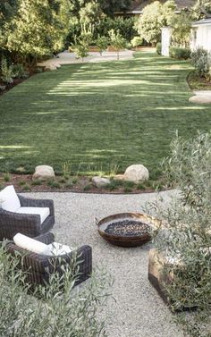 an outdoor living area with chairs, tables and fire pit in the middle of it