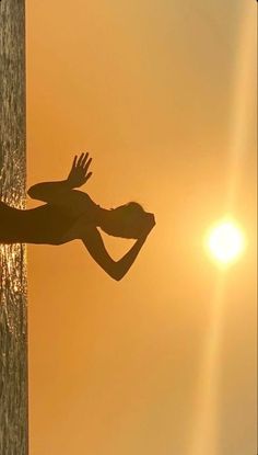 the silhouette of a person standing on top of a beach next to the ocean at sunset