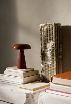 a stack of books sitting on top of a table next to a mushroom shaped lamp