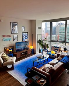 a living room filled with furniture and a large window covered in lots of windows overlooking the city