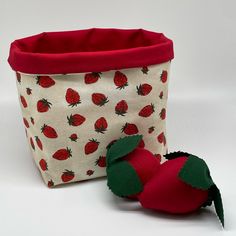 a stuffed strawberry sitting next to a fabric basket