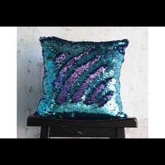 a blue and purple sequin pillow sitting on top of a wooden chair next to a wall