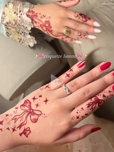 a woman's hands with henna tattoos on her left hand and red nail polish