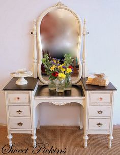 a white vanity with flowers on it and a mirror