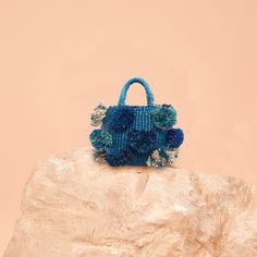 DESCRIPTION The bowl-like shaped blue designer pom pom bag is ethically handmade in Ghana. Using several shades of blue to create playful pom poms, this is a must have purse for summer. The pom pom bag is made of woven raffia with a linen lining and leather detailing and has a drawstring closure. This fashion-forward African handbag makes for a great companion for a lunch date or intimate gatherings. Be ready to receive adoration and compliments on this stylish bag! DETAILS Handmade in Ghana Mea Pom Pom Bag, Ready To Receive, Lunch Date, Blue Tassel, Woven Raffia, Tassel Bag, How To Make Handbags, Beaded Bags, Leather Key