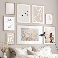 a bed with white sheets, pillows and pictures on the wall above it in a bedroom