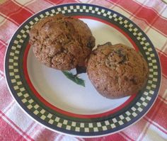 two chocolate muffins sitting on top of a white and black plate with red checkered table cloth