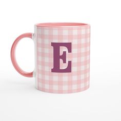 a pink and white checkered coffee mug with the letter e on it's side