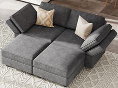 a gray couch with two pillows on it and a rug in the background that has a white diamond pattern