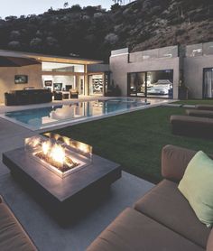 a fire pit in the middle of a patio next to a swimming pool at night