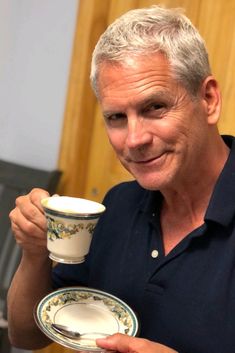 a man holding a coffee cup and saucer