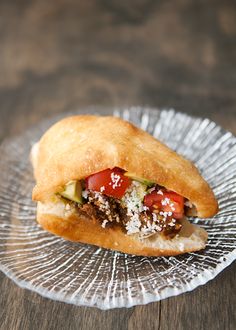 a sandwich with meat and vegetables is on a glass plate