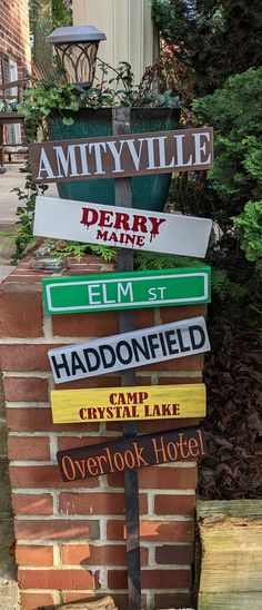 several street signs are stacked on top of each other in front of a brick building