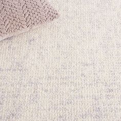 a close up view of a white carpet with a pillow on it and a rug in the background