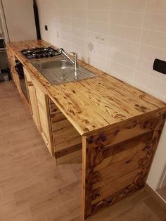 a kitchen counter made out of pallet wood with a sink and stove top in the middle