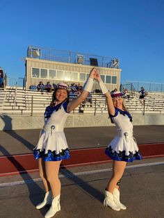 two cheerleaders in white and blue outfits are dancing