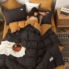 a woman laying on top of a bed covered in black and brown sheets with pillows