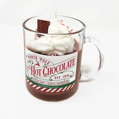 hot chocolate in a glass mug with whipped cream and candy canes on top, ready to be eaten