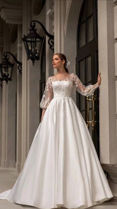 a woman in a white wedding dress standing on the steps with her arms out and looking off to the side