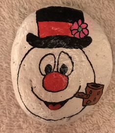 a painted rock with a snowman holding a piece of chocolate in it's hand