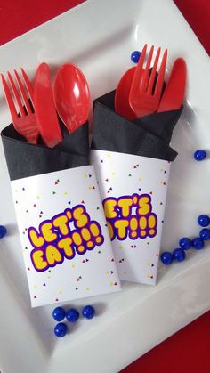 two red plastic utensils sitting on top of a white plate next to each other