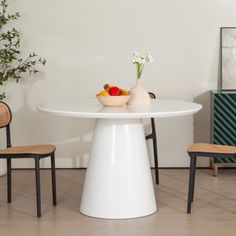 a white table with two chairs and a bowl of fruit on the plate next to it