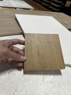 a hand is touching the edge of a piece of wood